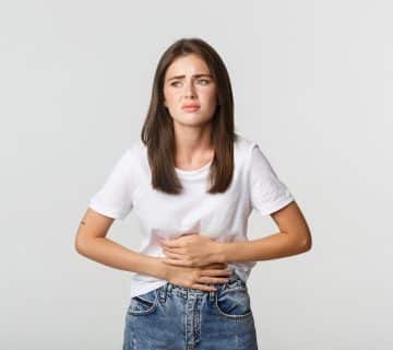 Woman having stomach ache bending with hands belly discomfort from menstrual cramps 360x320